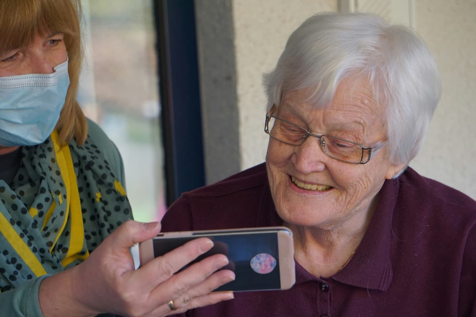Pečovatelka ukazuje seniorce telefon